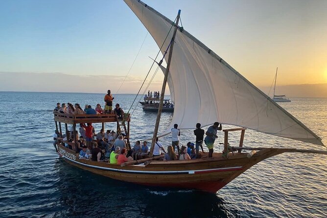 Traditional wooden dhow boats resting on the calm white sand beach shores of Bagamoyo at sunset