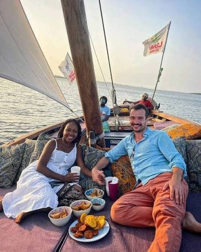 Traditional handcrafted wooden dhow sailing close to the Mahale Mountain ridges at sunset