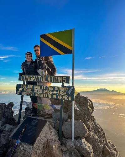 The dramatic narrow ridge line of Mount Meru peak with clouds below and Mount Kilimanjaro in the distance at sunrise