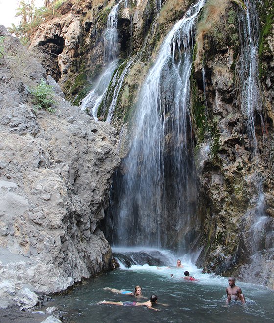Trekker hiking through a cool water stream canyon toward Engare Sero waterfalls