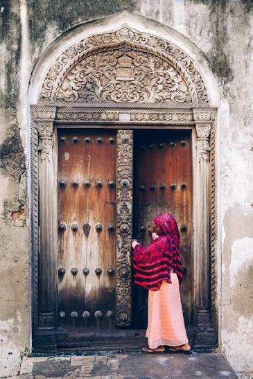 Intricate traditionally carved heavy wooden door in Stone Town Zanzibar showing brass studs